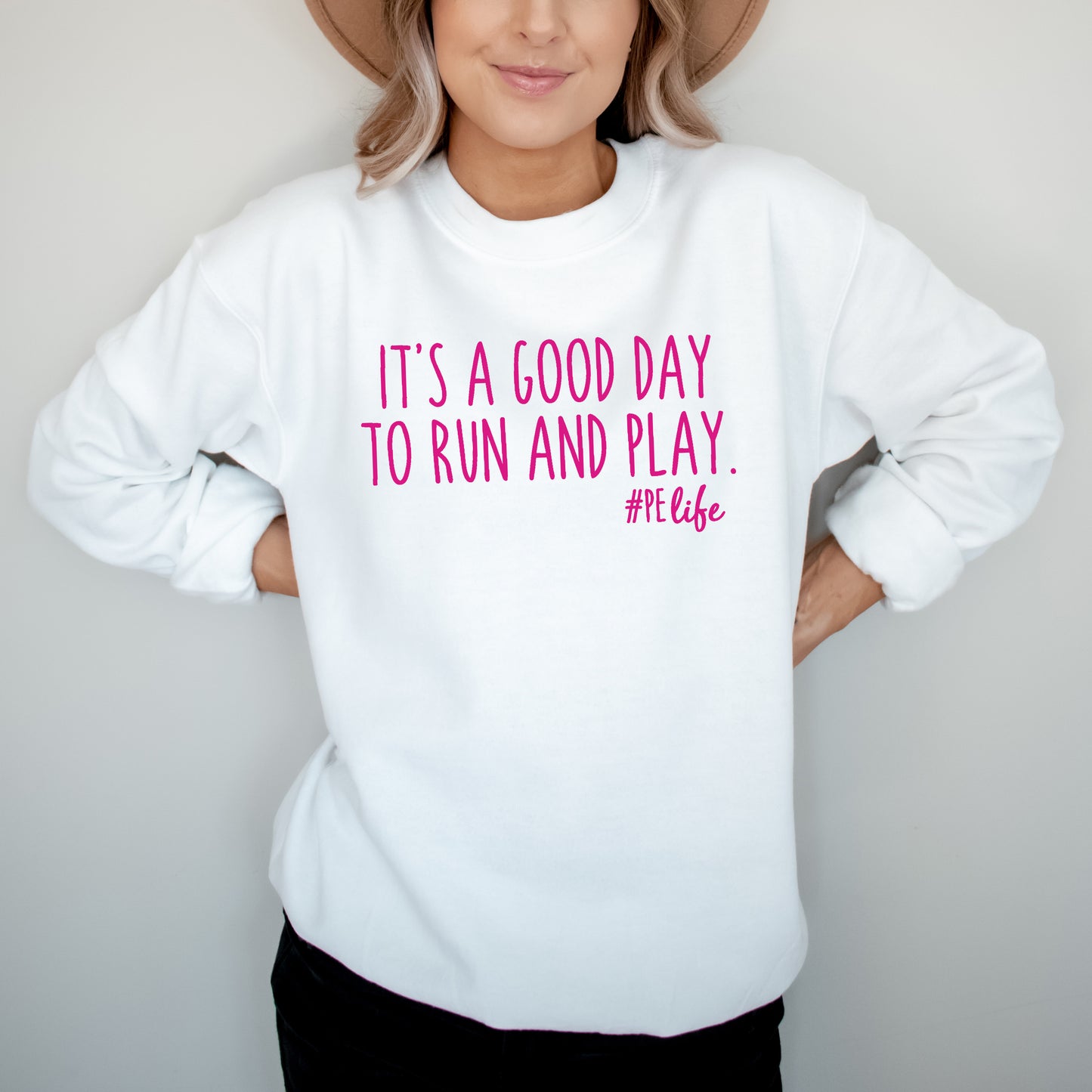 Woman wearing a white Gildan sweatshirt that says It's a Good Day to Run and Play #PE life