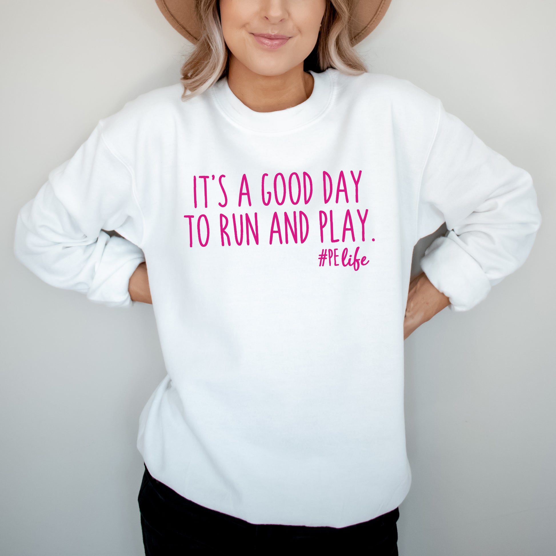 Woman wearing a white Gildan sweatshirt that says It's a Good Day to Run and Play #PE life