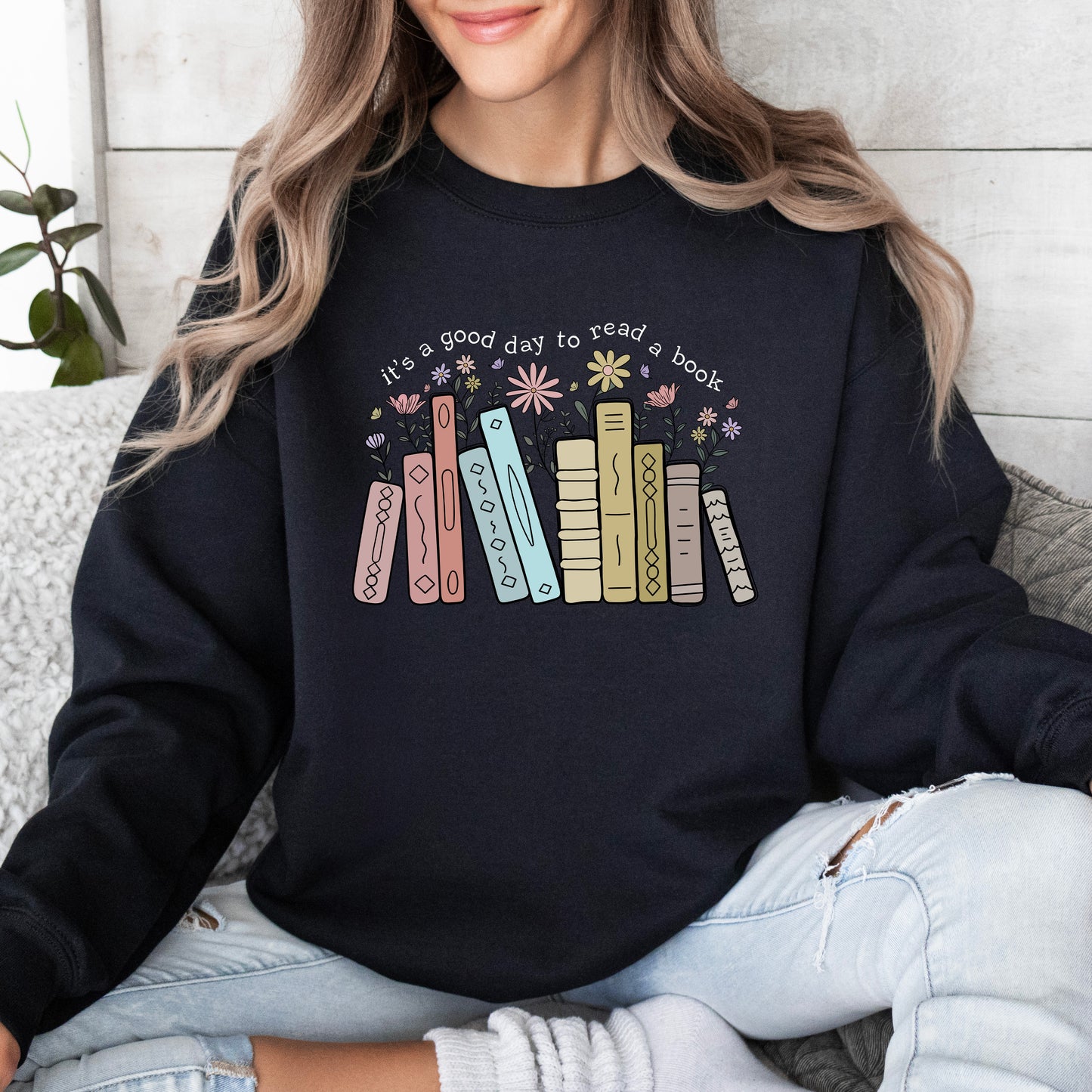 Person wearing a black sweatshirt with colorful book design and text.