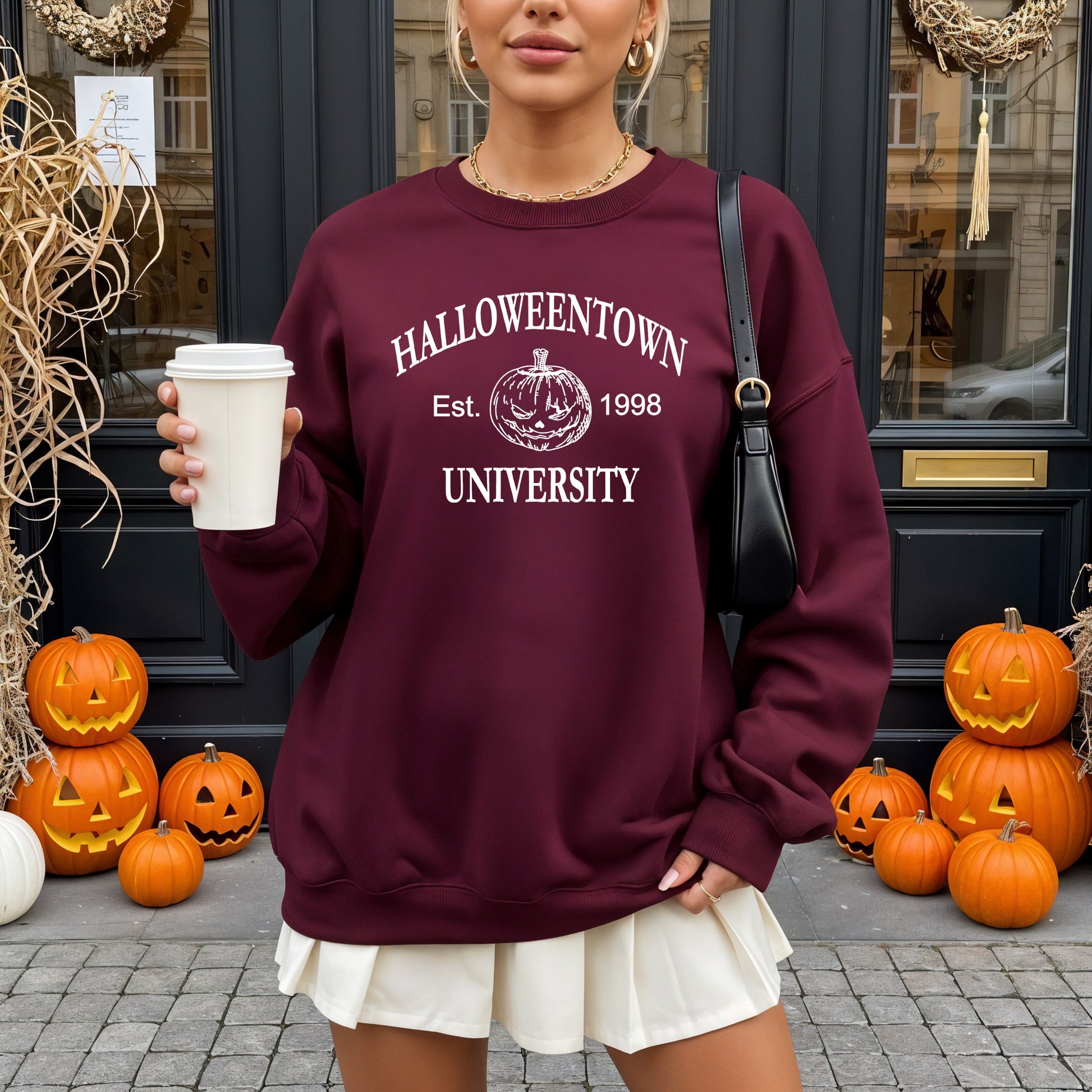 Woman wearing a maroon Gildan sweatshirt that says Halloweentown University Ets. 1998 and has a scary jack-o-lantern on it.