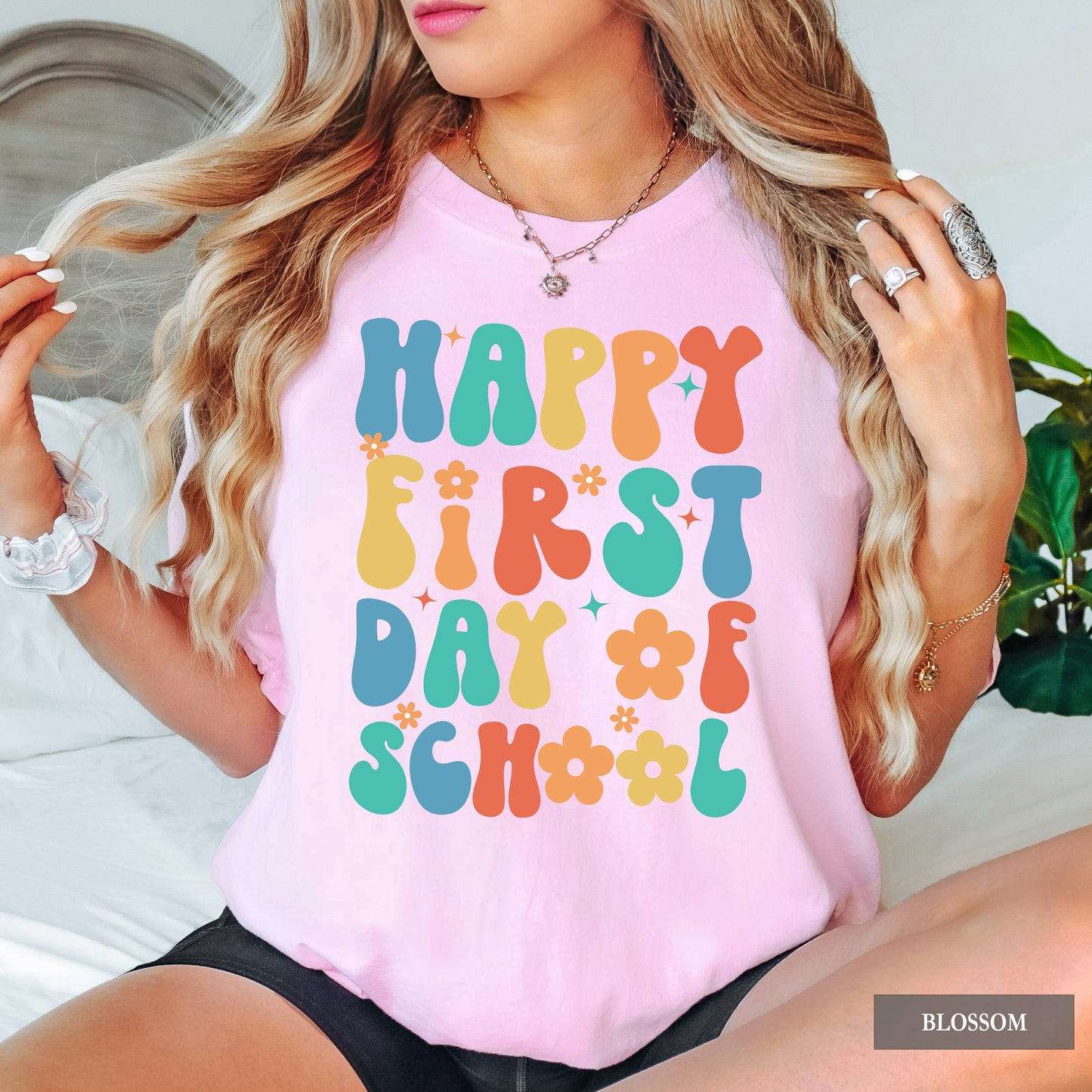 Person wearing a pink t-shirt with 'Happy First Day of School' text in colorful letters.