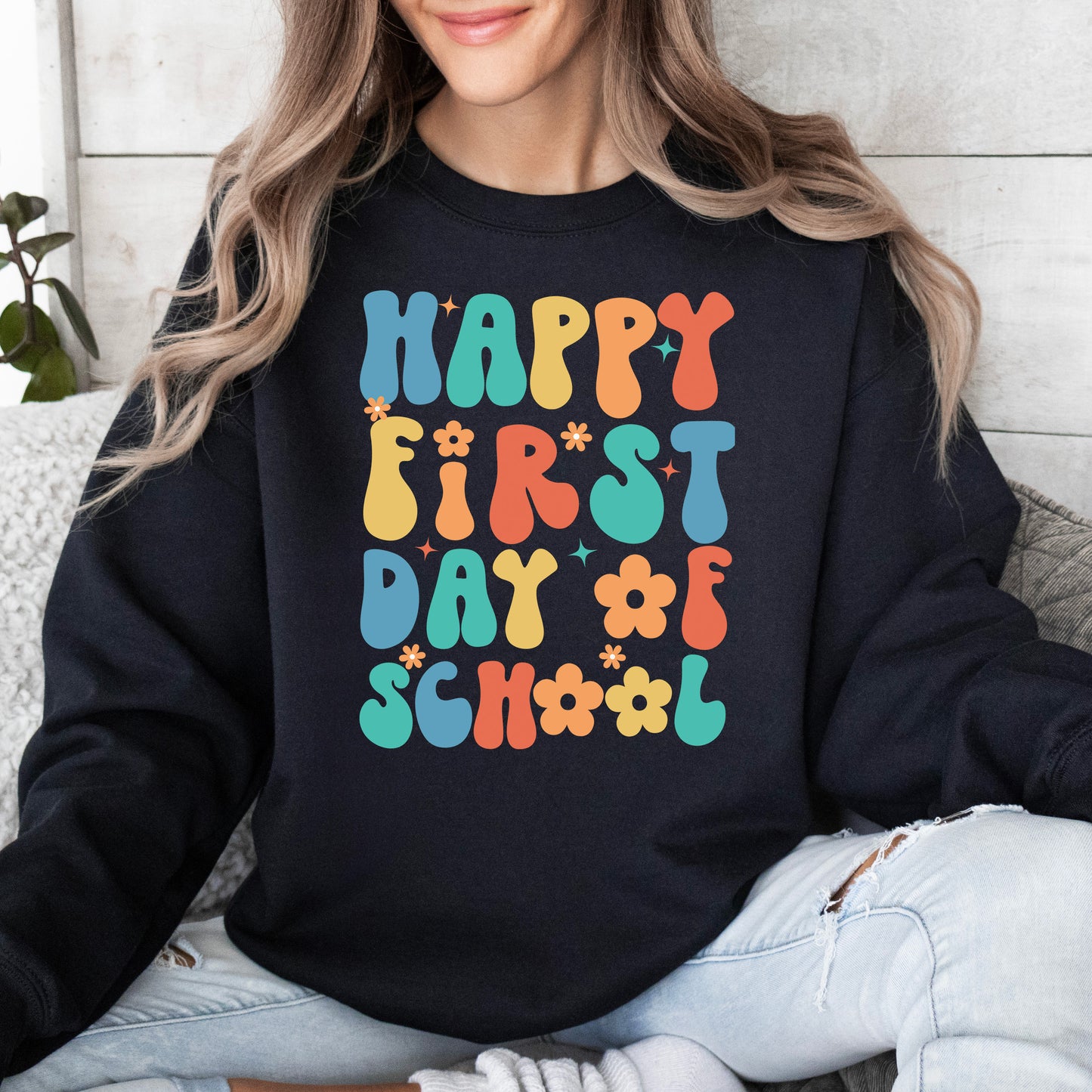 Person wearing a black sweatshirt with 'Happy First Day of School' in colorful letters.