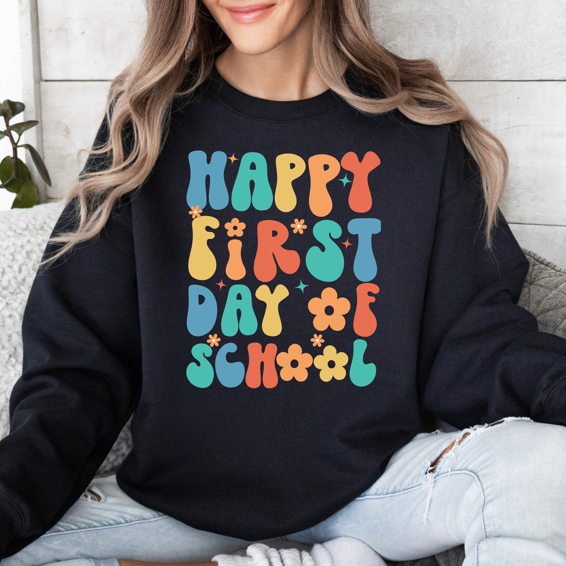 Person wearing a black sweatshirt with 'Happy First Day of School' in colorful letters.