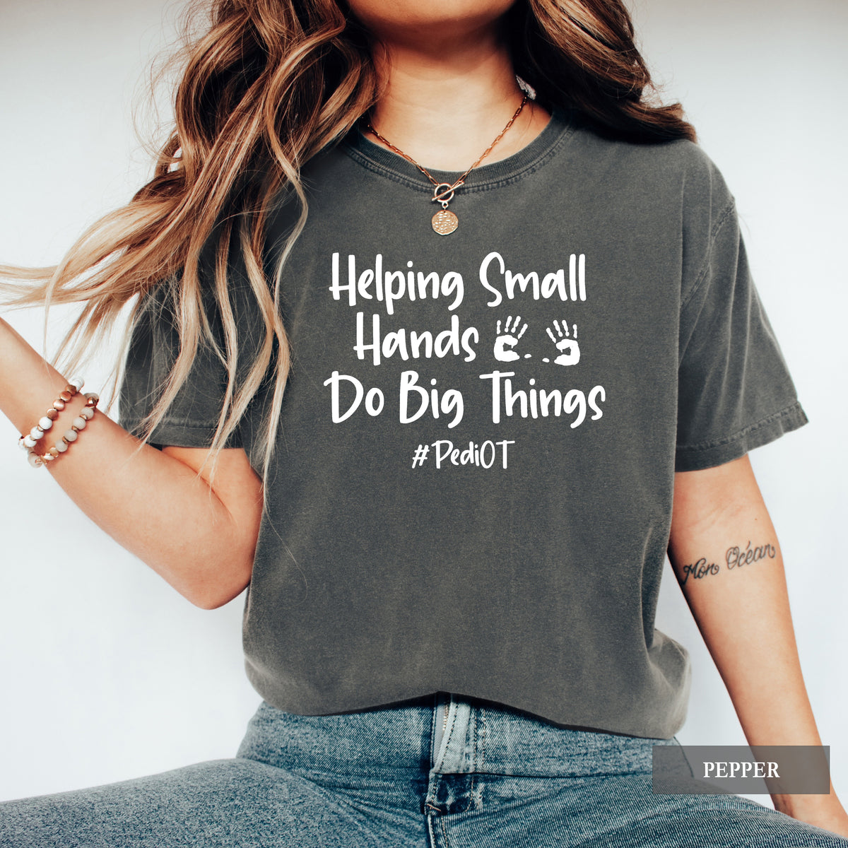 A woman wearing a pepper comfort colors shirt that says Helping Small Hands Do Big Things #PediOT