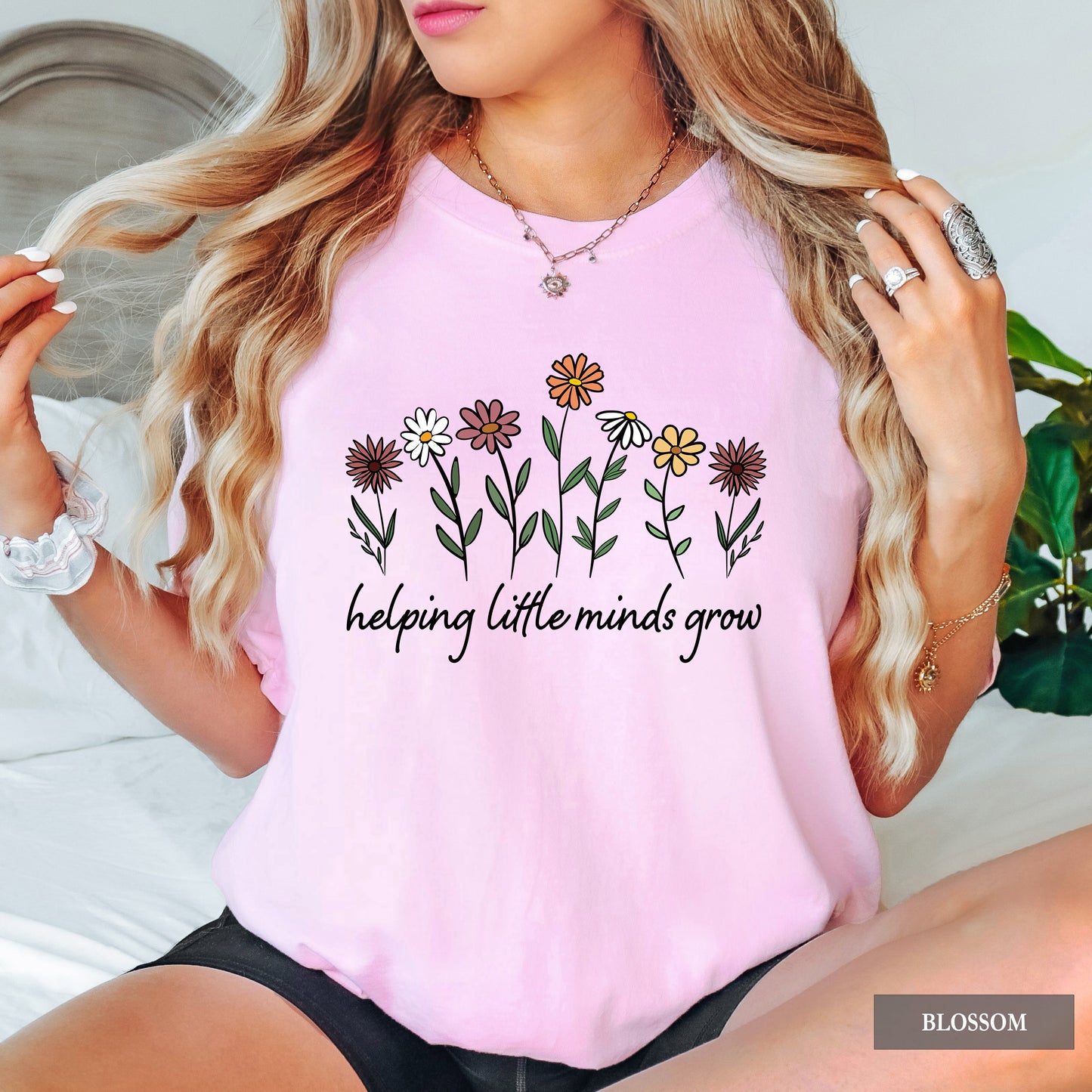Person wearing a pink t-shirt with floral design and text, sitting on a couch.