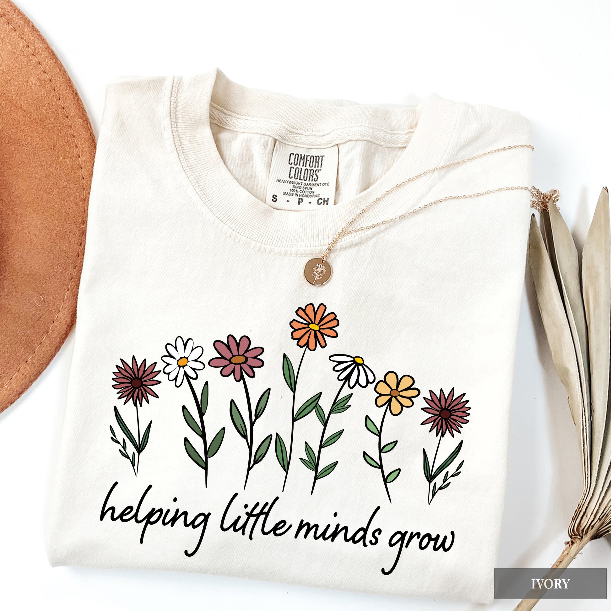 White shirt with floral design and 'helping little minds grow' text on a white background