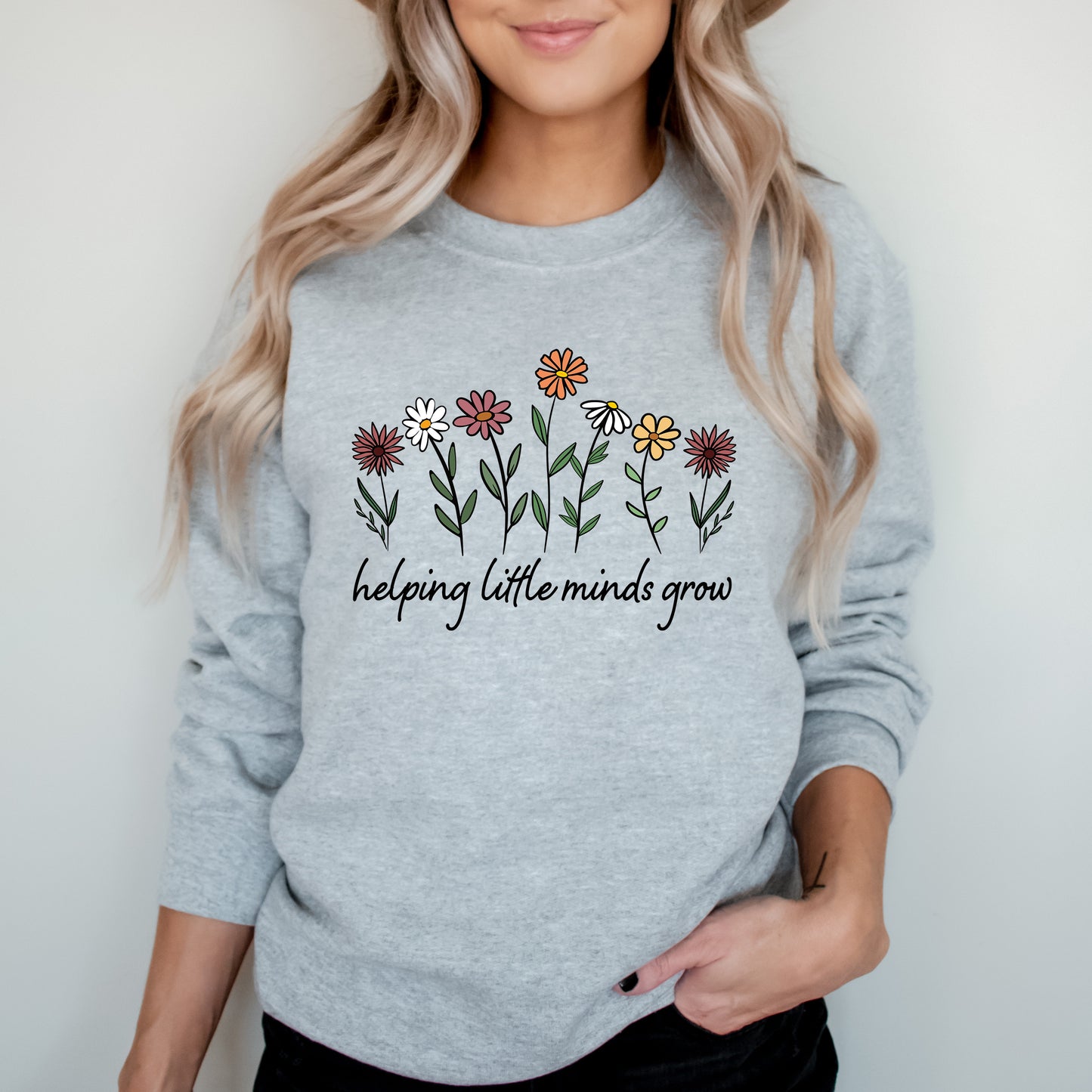 Person wearing a gray sweatshirt with floral design and text on a plain background
