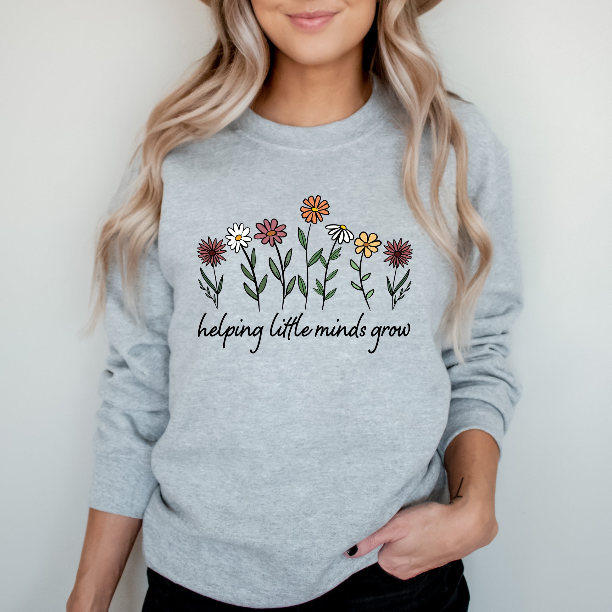 Person wearing a gray sweatshirt with floral design and text on a plain background