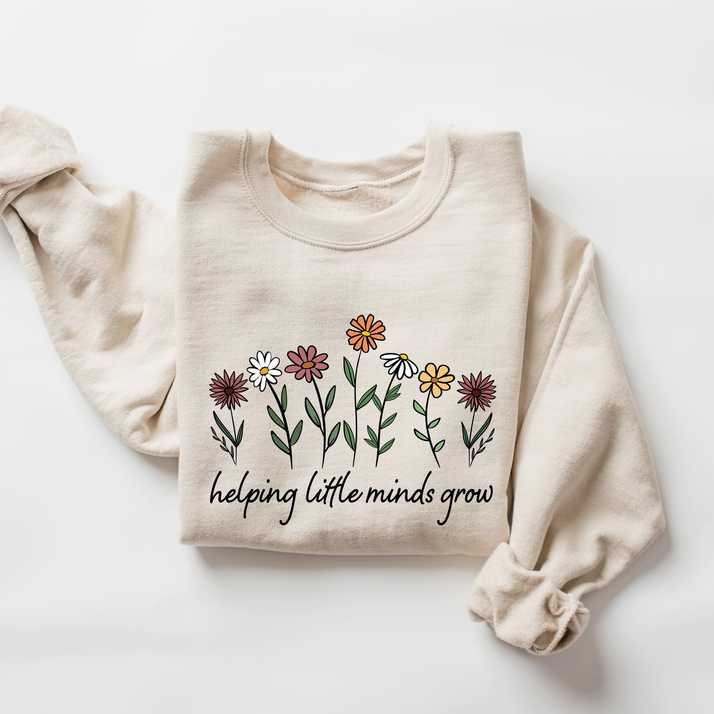 Beige sweatshirt with floral design and text 'helping little minds grow' on a white background