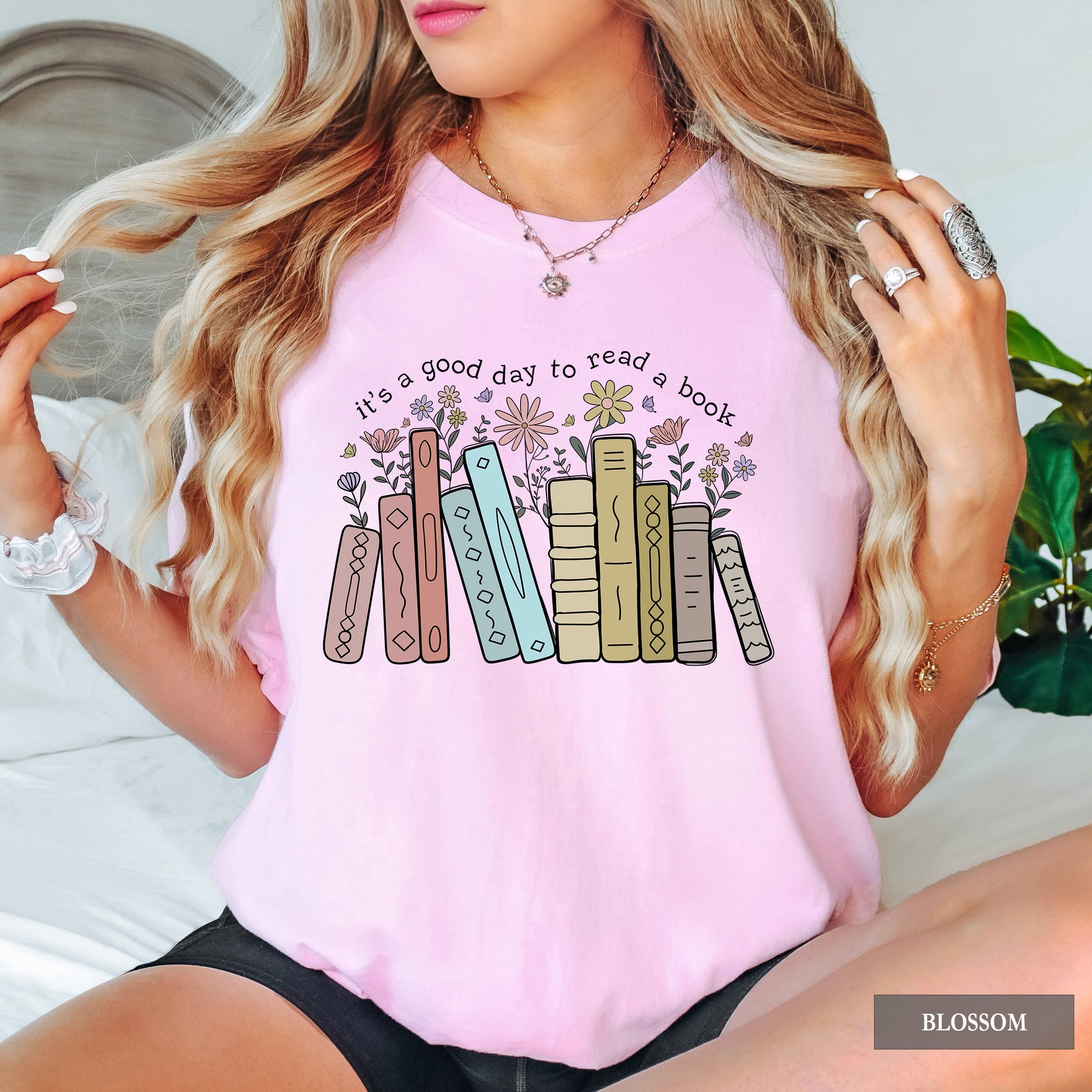 Person wearing a pink t-shirt with book graphic and text 'it's a good day to read a book'.