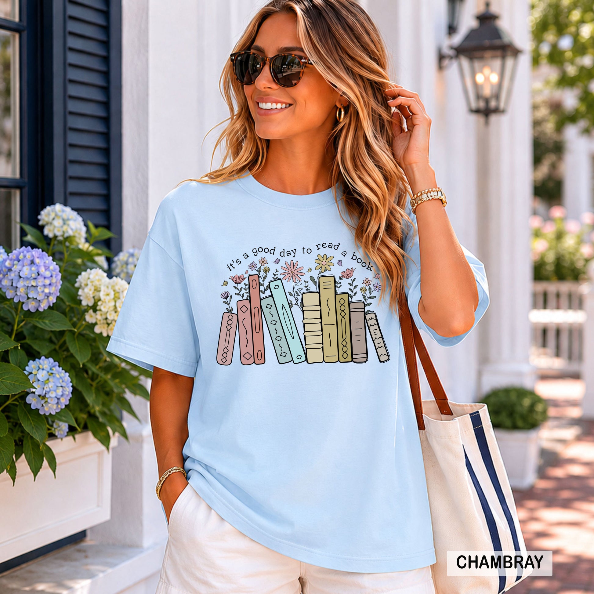 Woman wearing a light blue t-shirt with book graphic and text, standing outdoors.