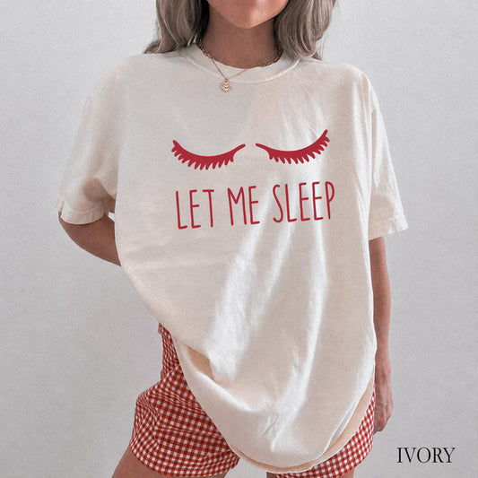A woman wearing an oversized ivory graphic T-shirt with red eyelashes and the words 'LET ME SLEEP' in red, paired with red-and-white gingham shorts. The image has a light gray background and the word 'IVORY' in the bottom right corner.