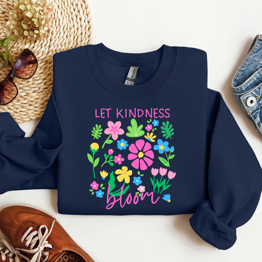 Navy blue sweatshirt with floral design and 'Let Kindness Bloom' text on a white surface.