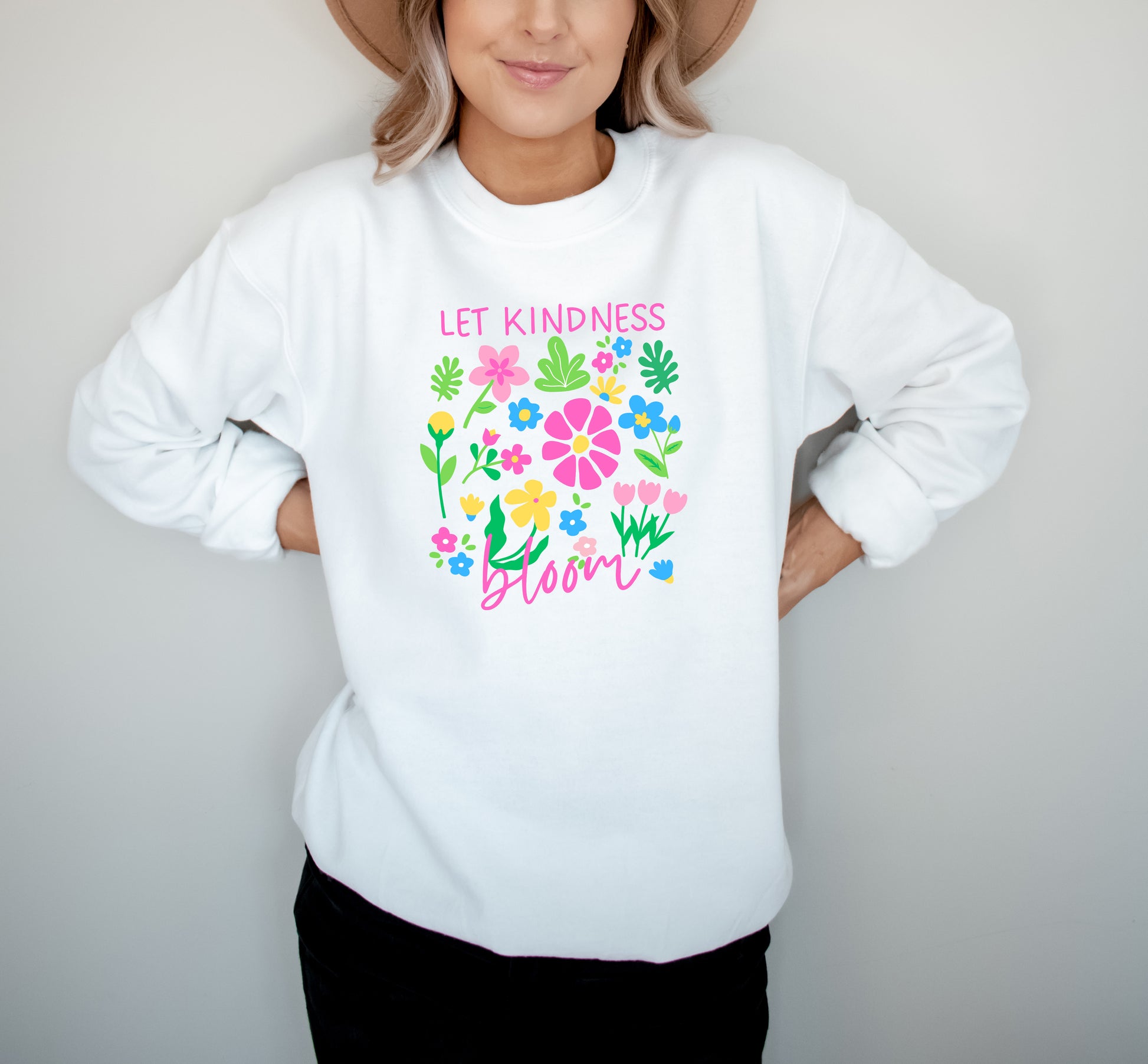 Person wearing a white sweatshirt with colorful floral design and text on a plain background