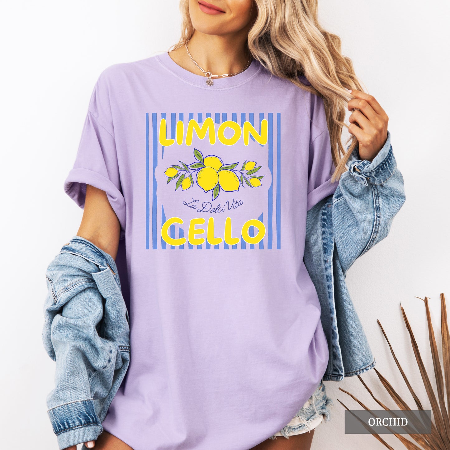 Person wearing a lavender t-shirt with lemon graphic and text, holding a denim jacket.