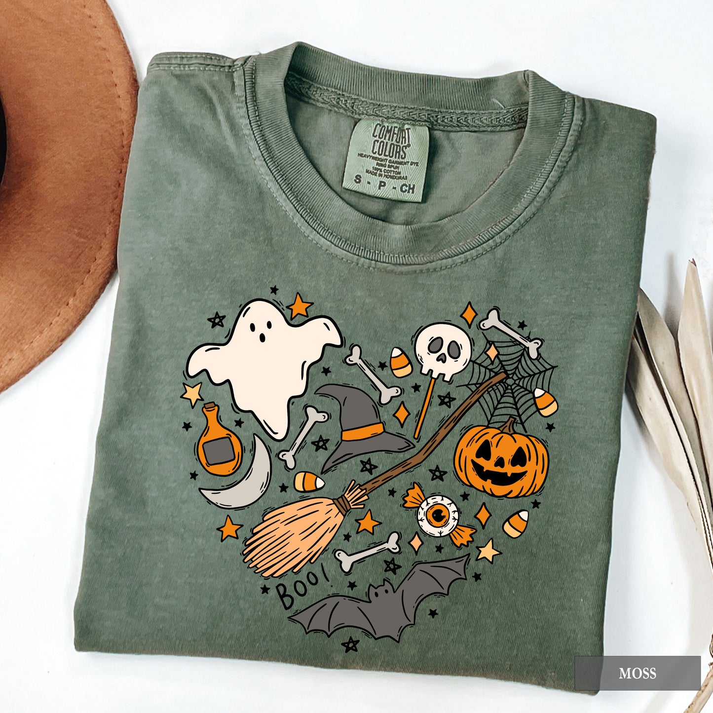 Folded green t-shirt with Halloween-themed graphics on a white surface