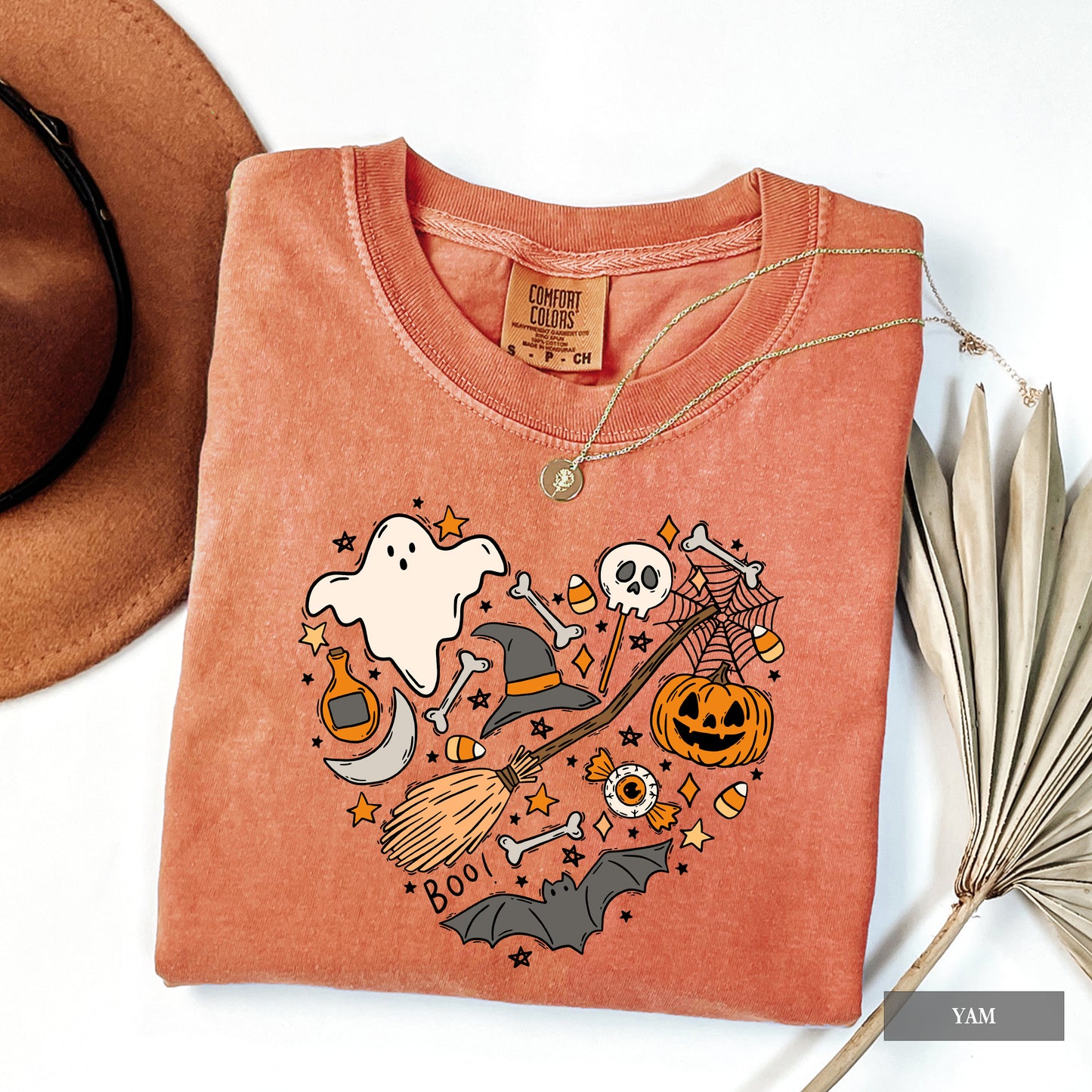 Folded orange t-shirt with Halloween-themed design on a white background