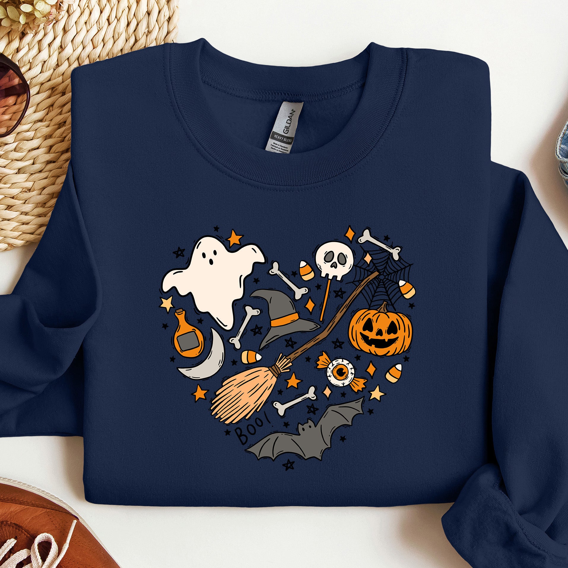 Navy blue sweatshirt with Halloween-themed design featuring a ghost, pumpkin, and broomstick on a white background.