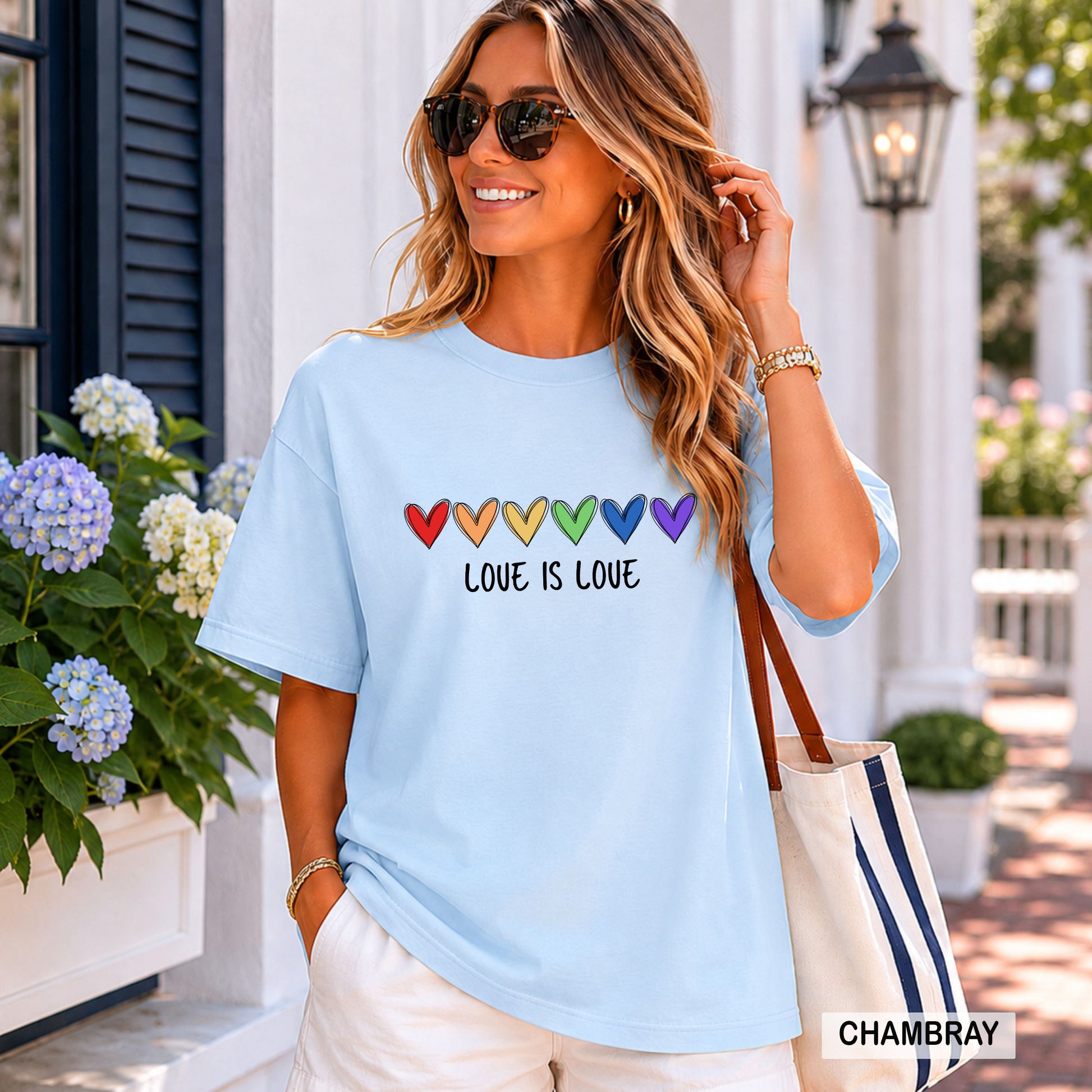 Woman wearing a light blue t-shirt with rainbow hearts and 'LOVE IS LOVE' text, standing outdoors.