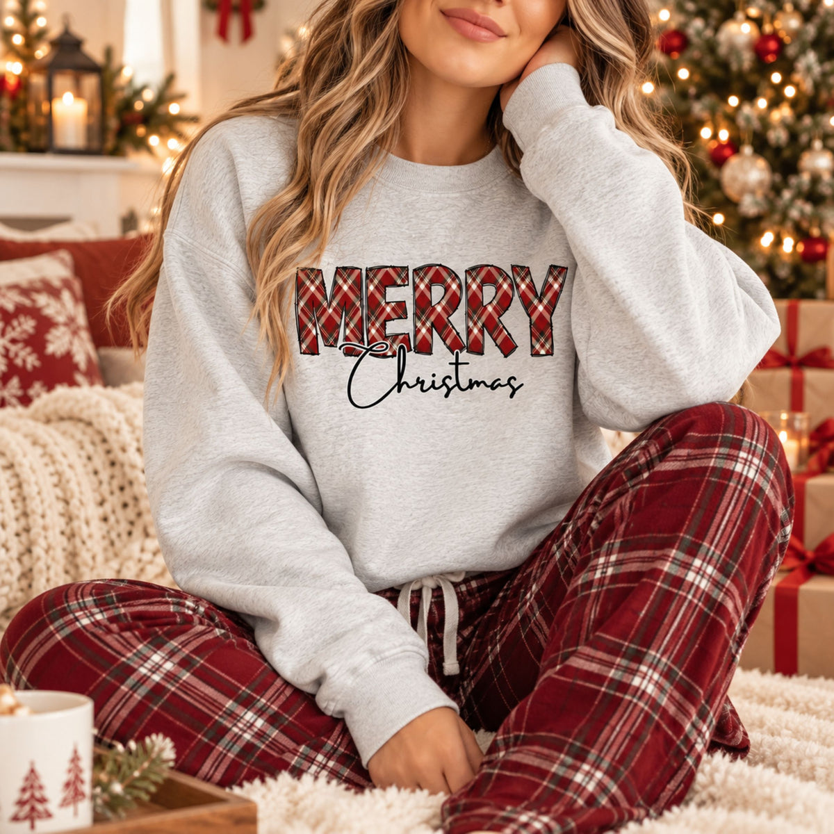 A woman wearing an Ash Gildan sweatshirt with Merry in plaid and Christmas below that in script font.