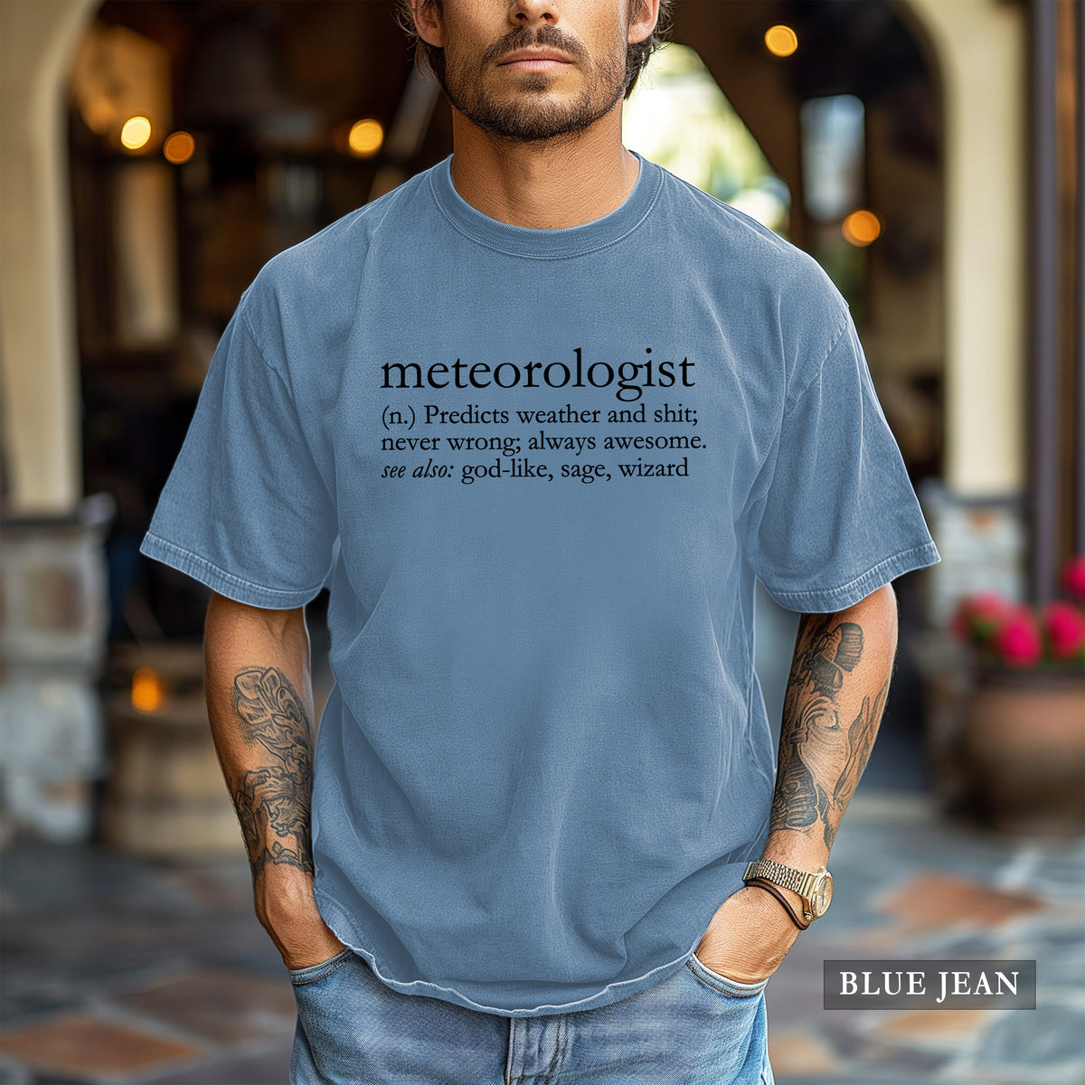 A man wearing a blue jean comfort colors shirt that says 'meteorologist (n.) Predicts weather and shit; never wrong; always awesome. see also: god-like, sage, wizard
