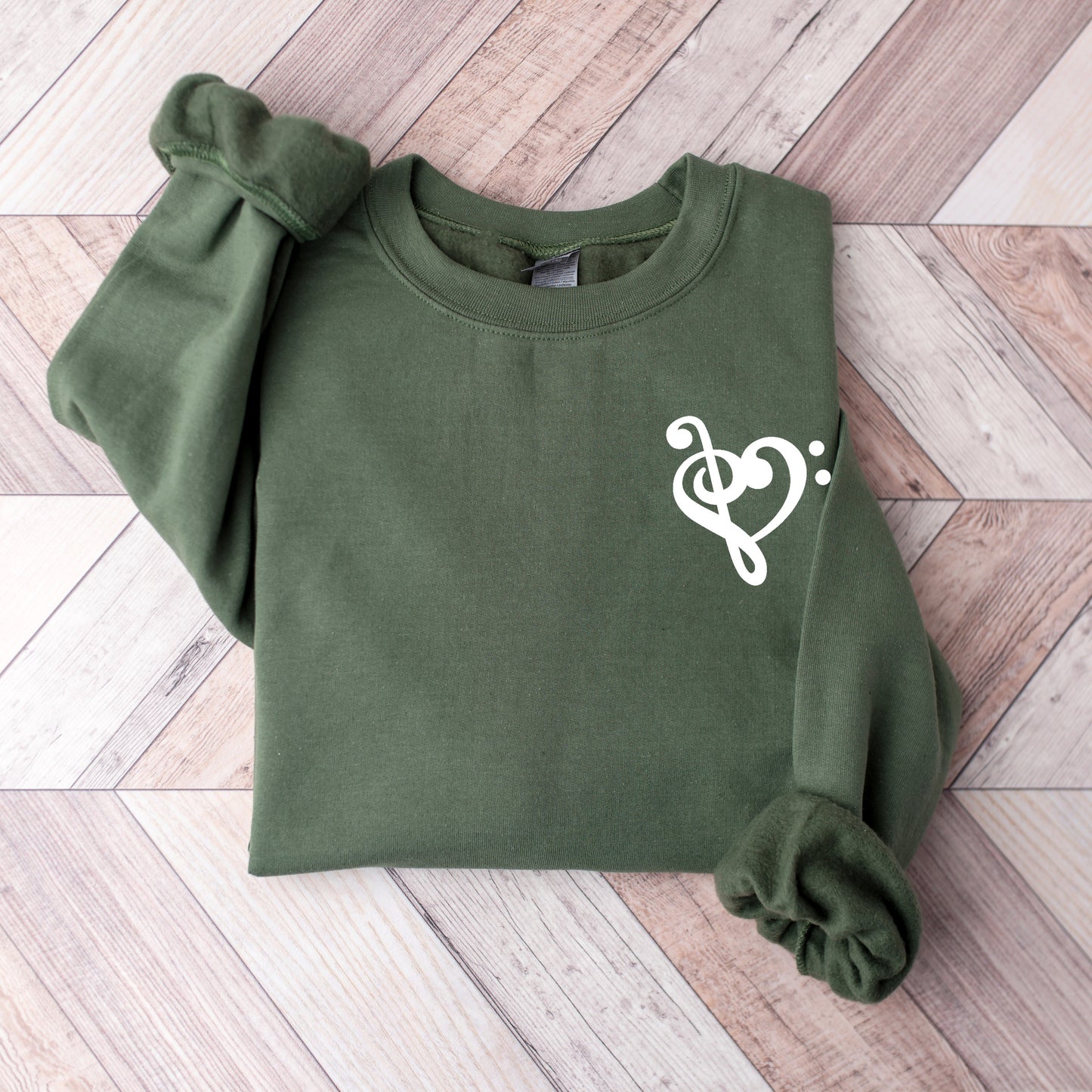 A military green gildan sweatshirt with a musical note shaped like a heart on the pocket area.
