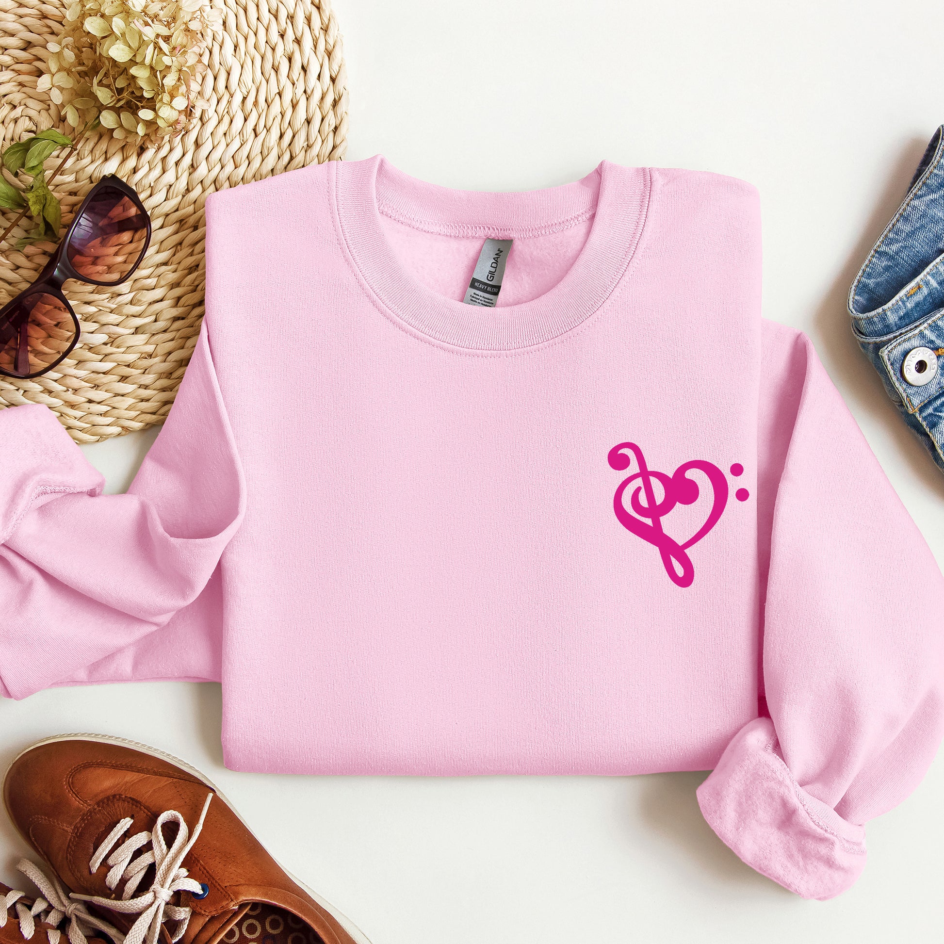 A pink gildan sweatshirt with a musical note shaped like a heart on the pocket area.
