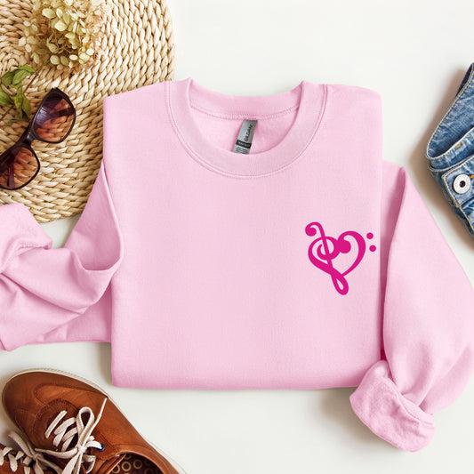 A pink gildan sweatshirt with a musical note shaped like a heart on the pocket area.
