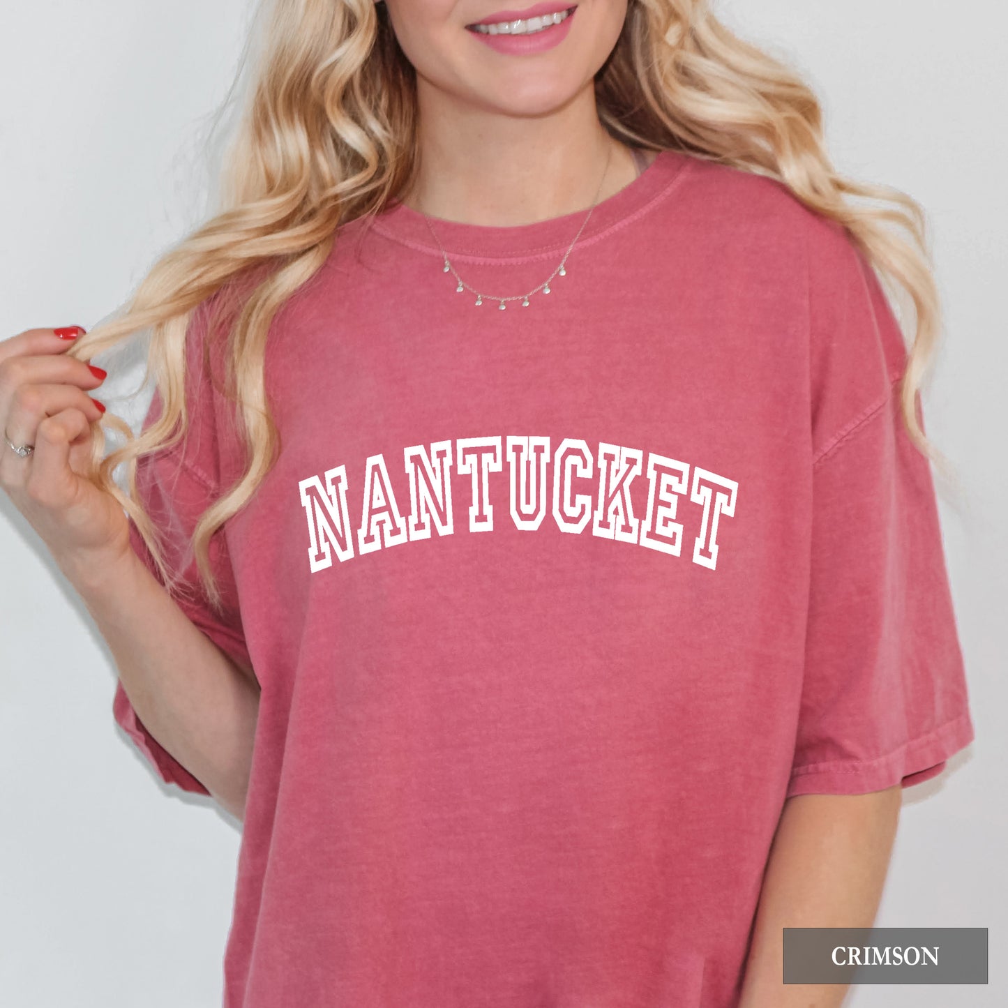 Woman wearing a crimson comfort colors shirt that says Nantucket.