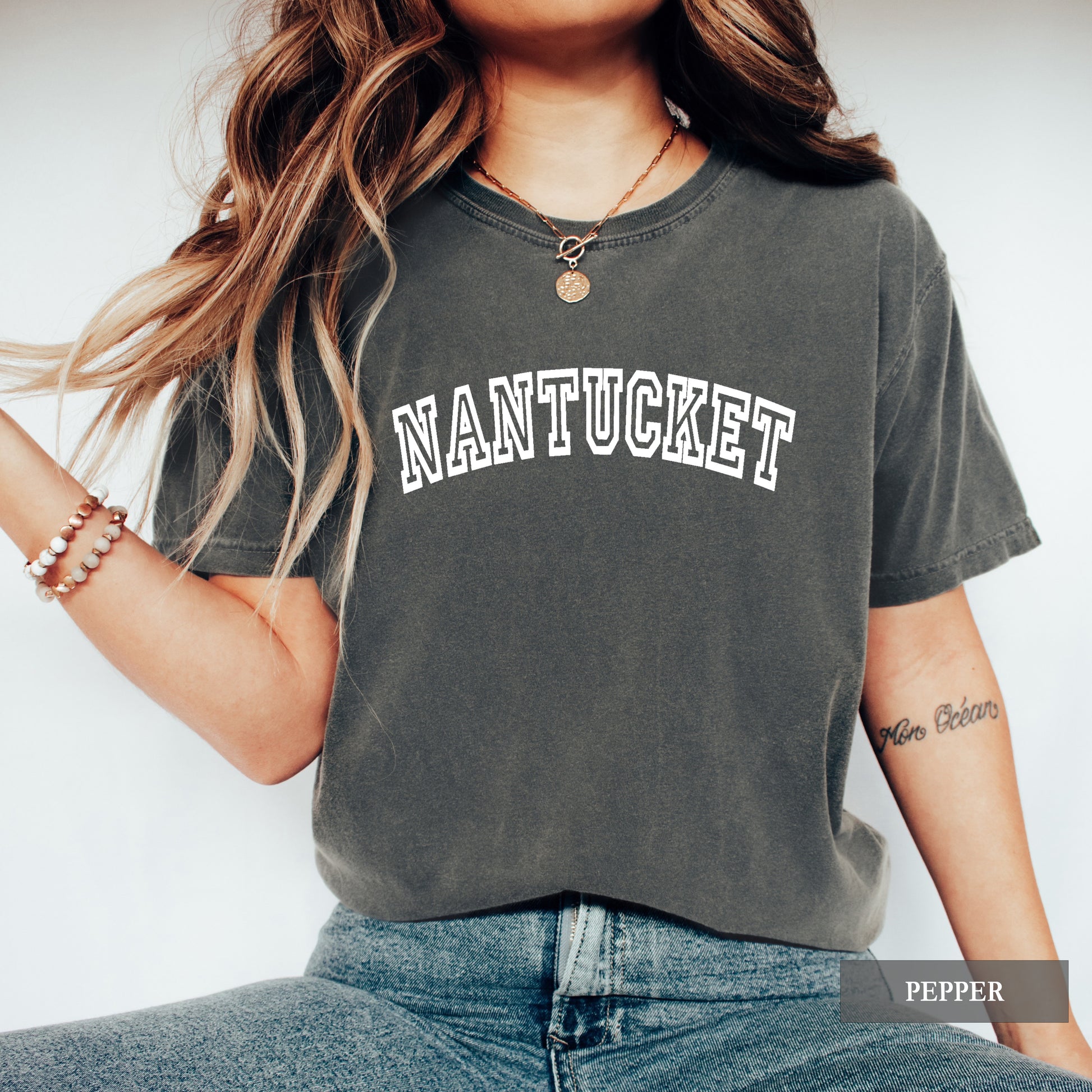 Woman wearing a pepper comfort colors shirt that says Nantucket.