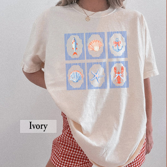 Person wearing a beige t-shirt with a graphic design showing nautical and seaside icons like starfish, sea shells, a lobster and a fish on a plain background