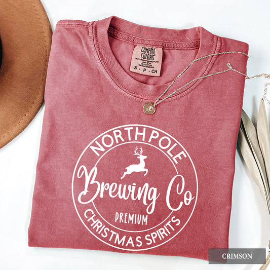 A crimson comfort colors shirt with 'North Pole Brewing Co' on it in white print.