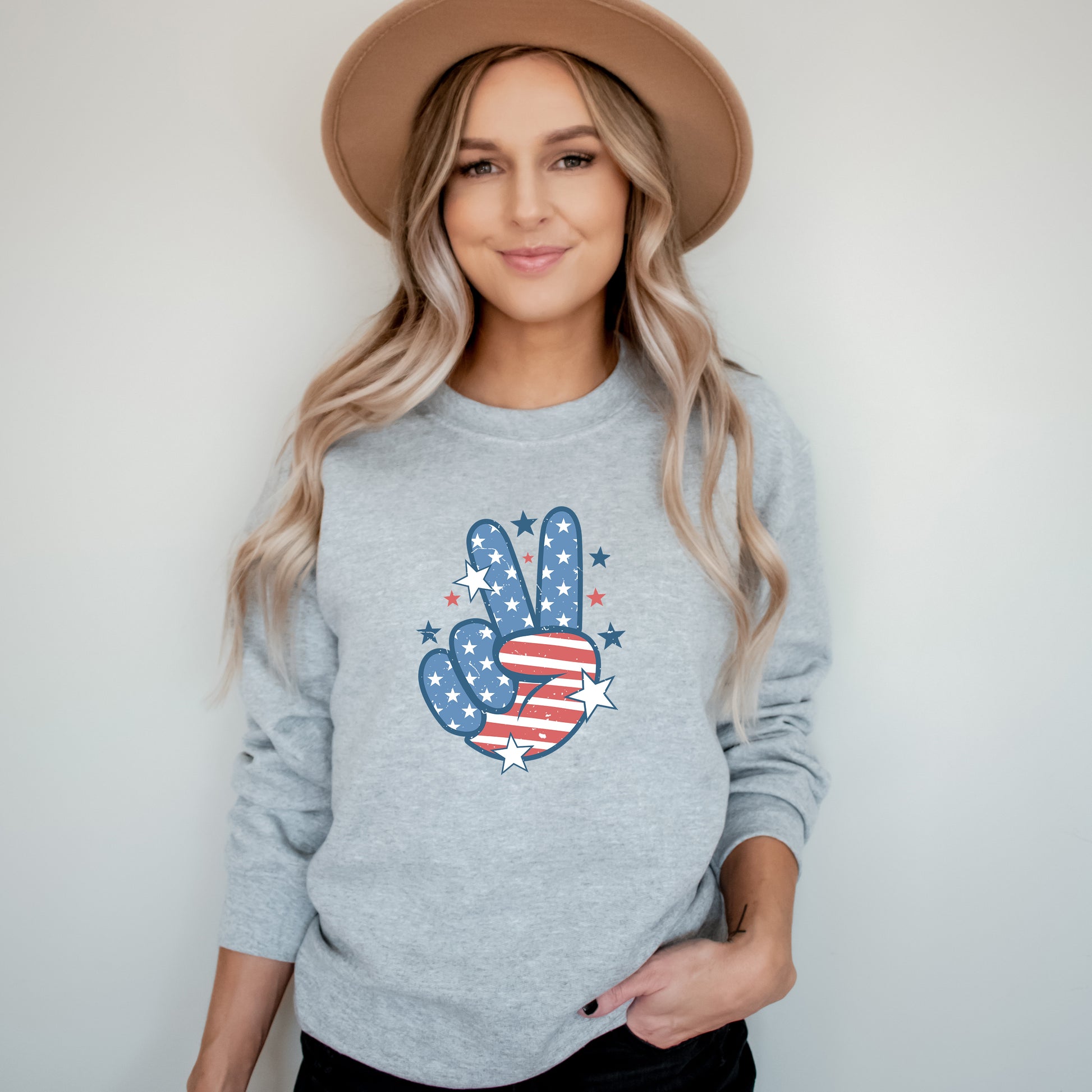 Woman wearing a gray sweatshirt with a peace sign design, standing against a plain background.