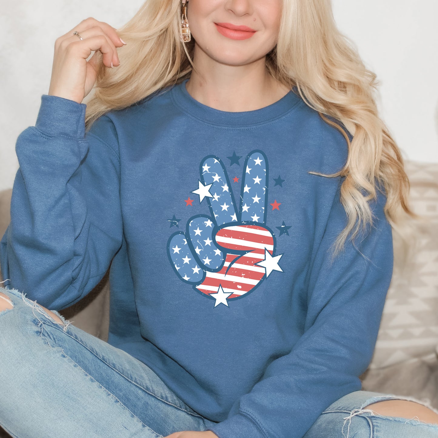 Person wearing a blue sweatshirt with a hand peace sign design featuring stars and stripes.
