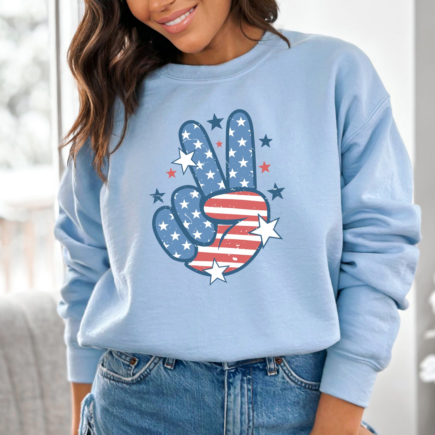 Light blue sweatshirt with American flag hand gesture design worn by a person.
