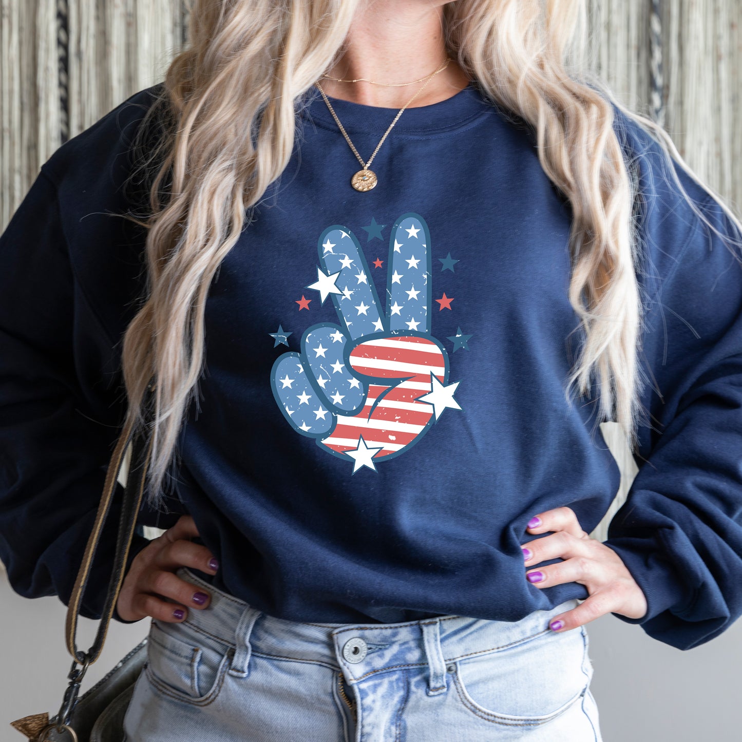 Person wearing a navy blue sweatshirt with a peace sign design featuring stars and stripes.