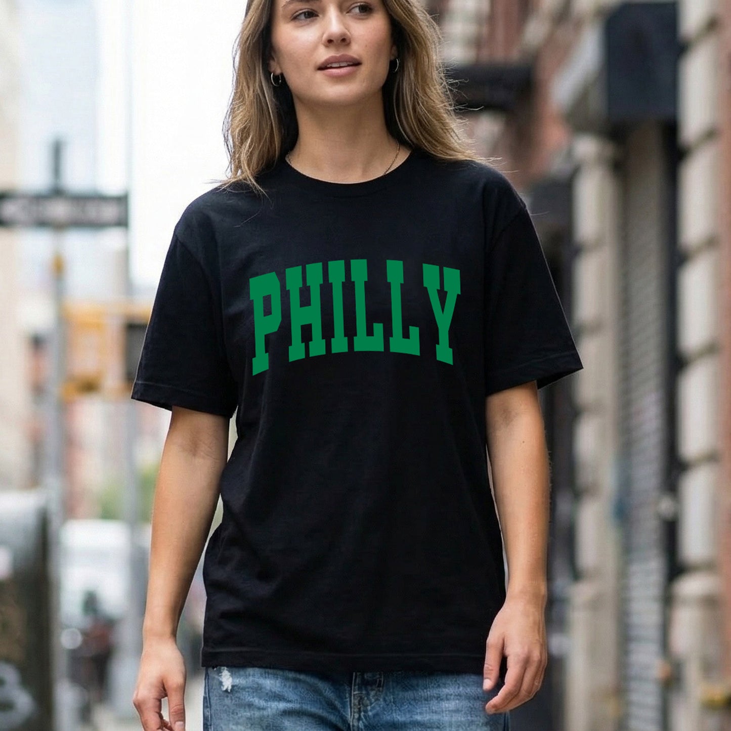 Woman wearing a black comfort colors t-shirt that says Philly on the front.