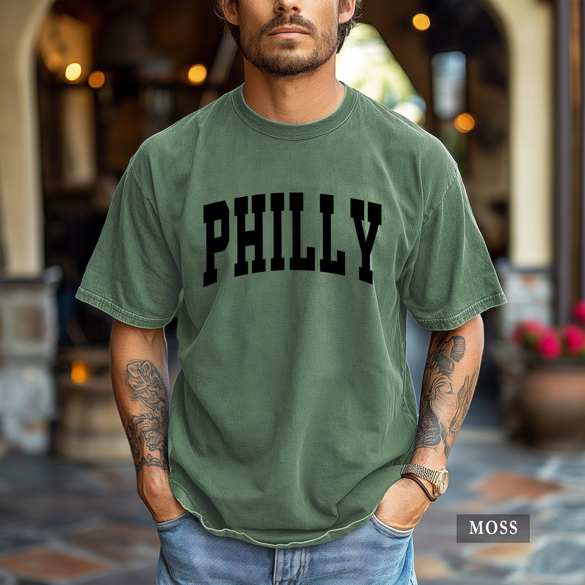 Man wearing a moss comfort colors t-shirt that says Philly on the front.