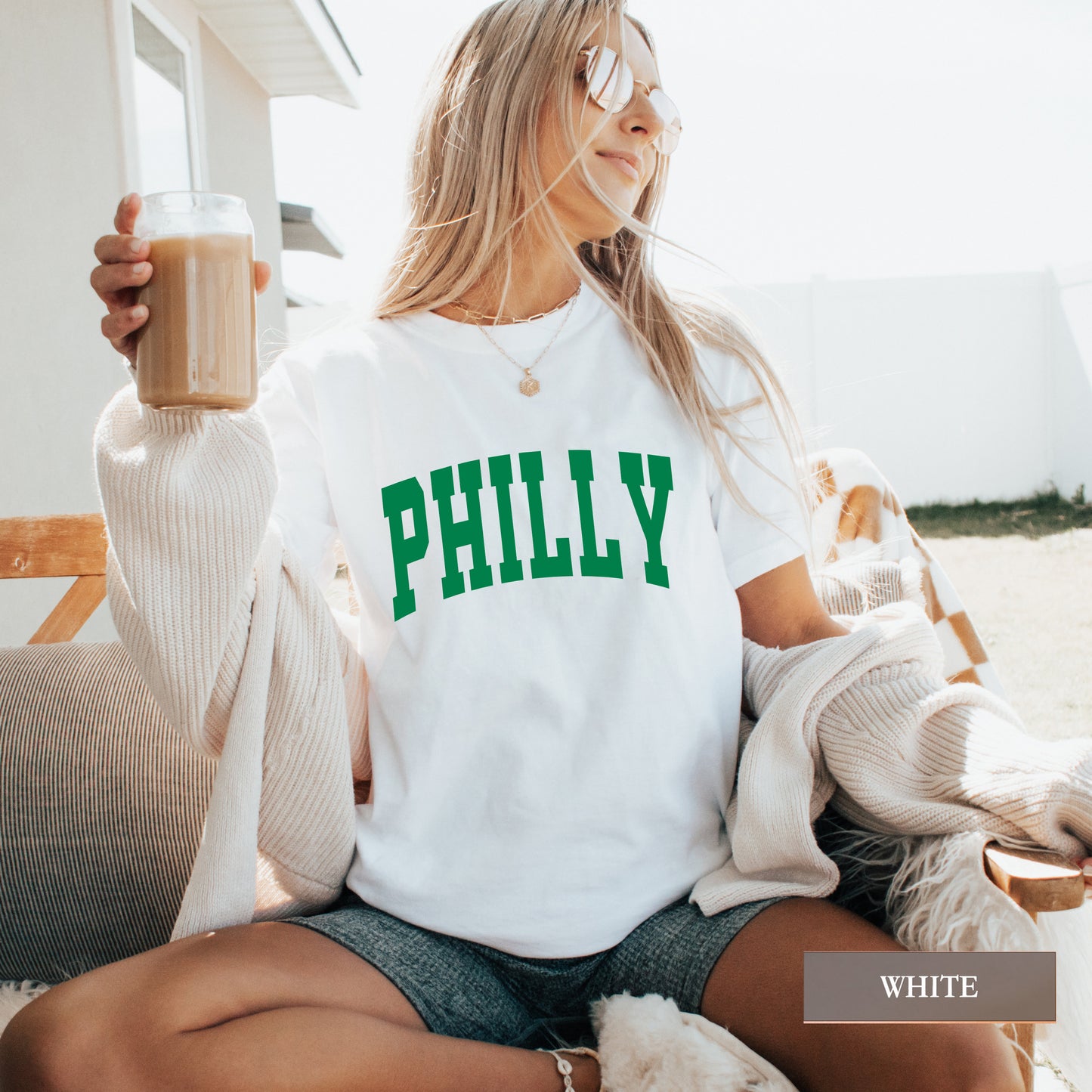 Woman wearing a white comfort colors t-shirt that says Philly on the front.
