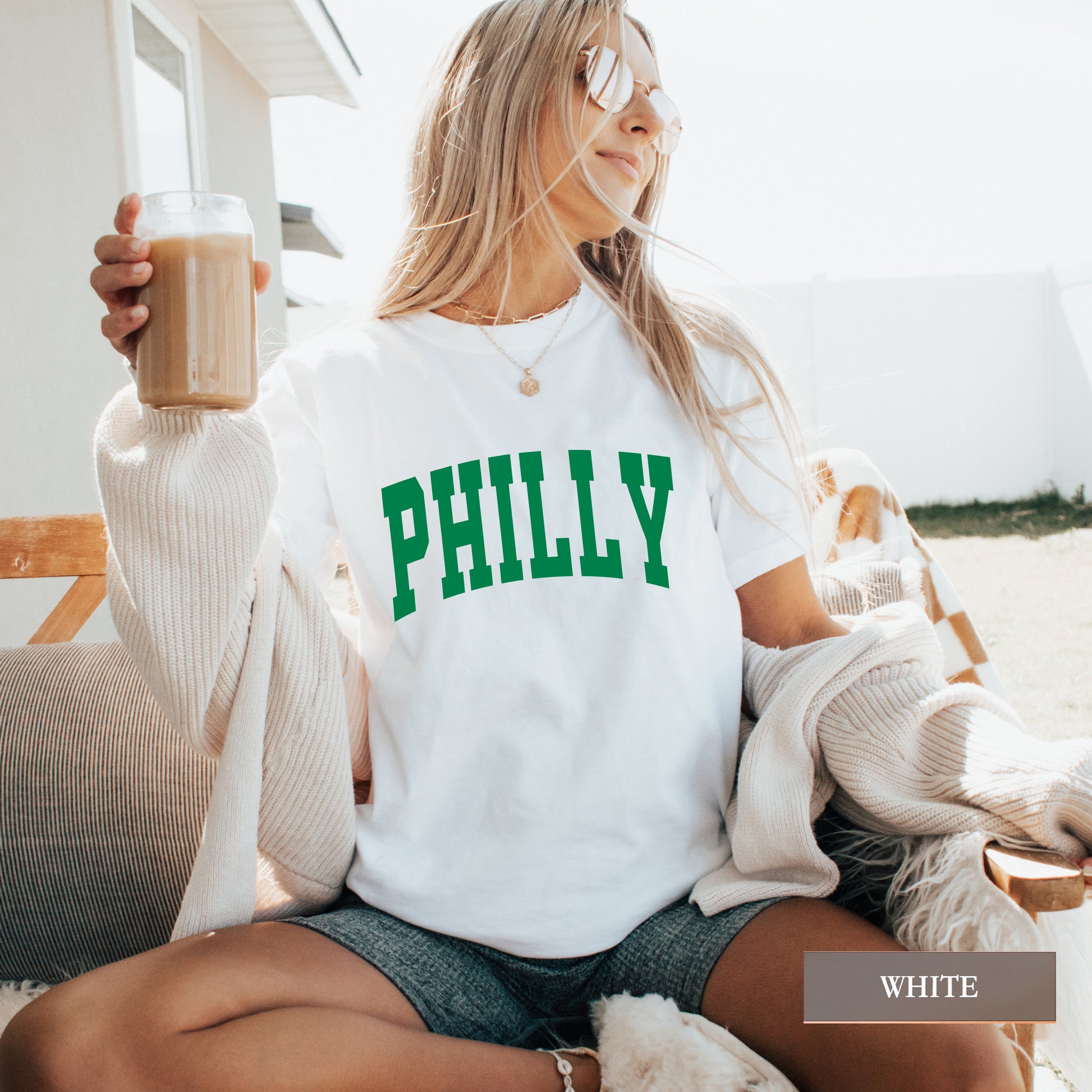 Woman wearing a white comfort colors t-shirt that says Philly on the front.