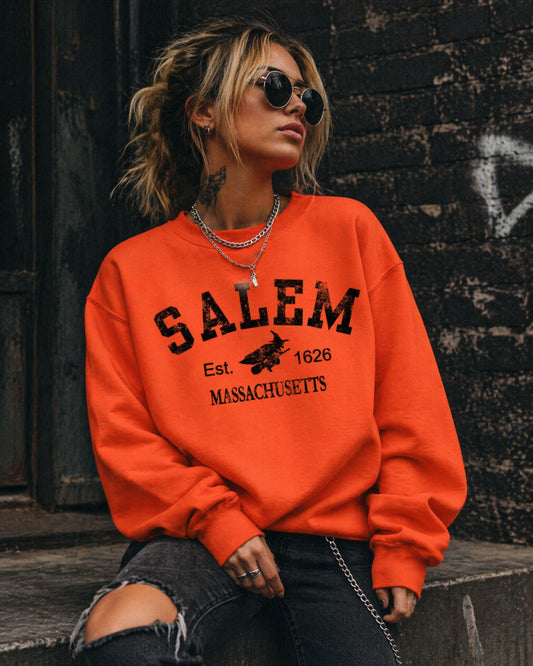 Person wearing an orange sweatshirt with 'Salem, Massachusetts' text against a dark wall.