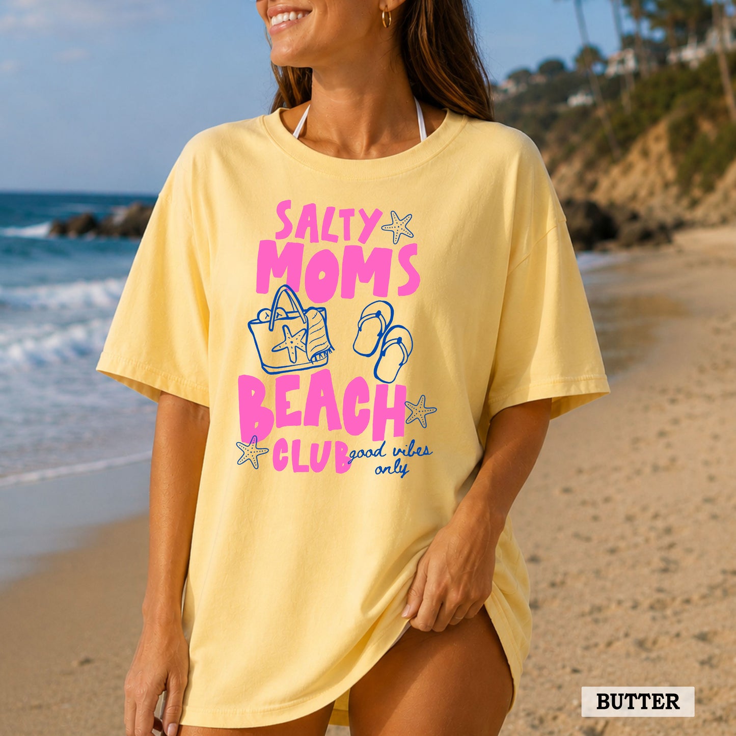 Woman wearing a yellow 'Salty Moms Beach Club' t-shirt on a beach.