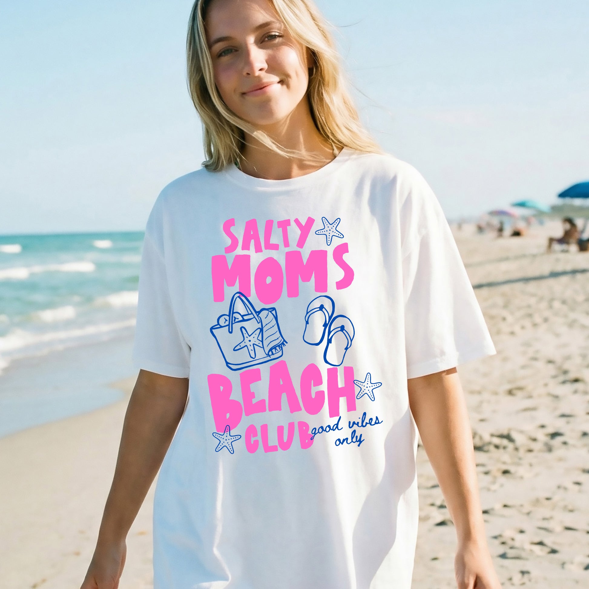 Woman wearing a 'Salty Moms Beach Club' t-shirt on a beach