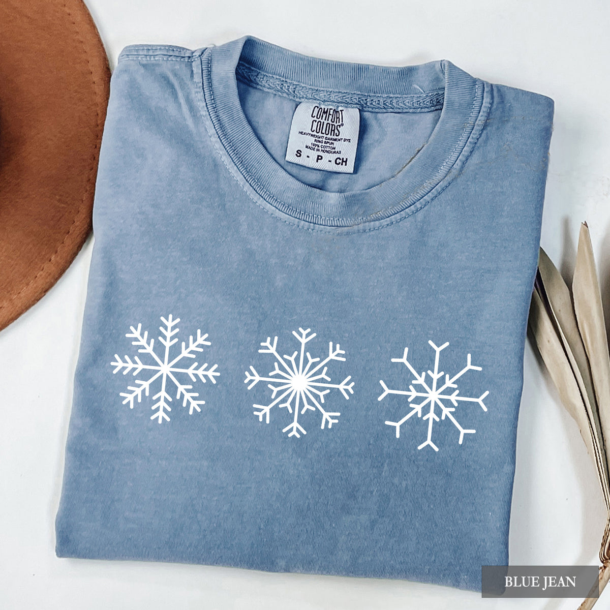 A blue jean comfort colors t-shirt with three snowflakes on the front.