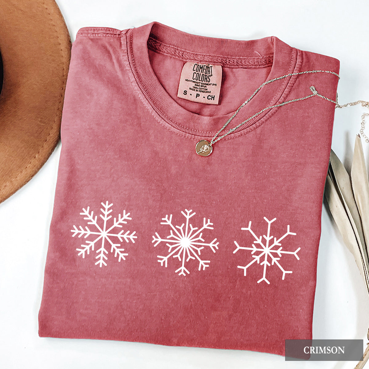A crimson comfort colors t-shirt with three snowflakes on the front.