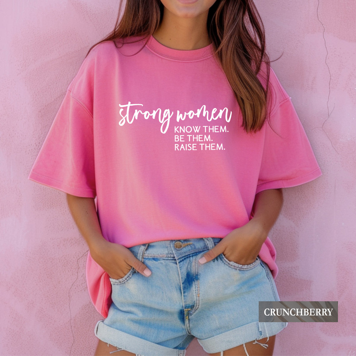A woman wearing a crunchberry comfort colors shirt that says 'Strong Women Know Them Be Them Raise Them.