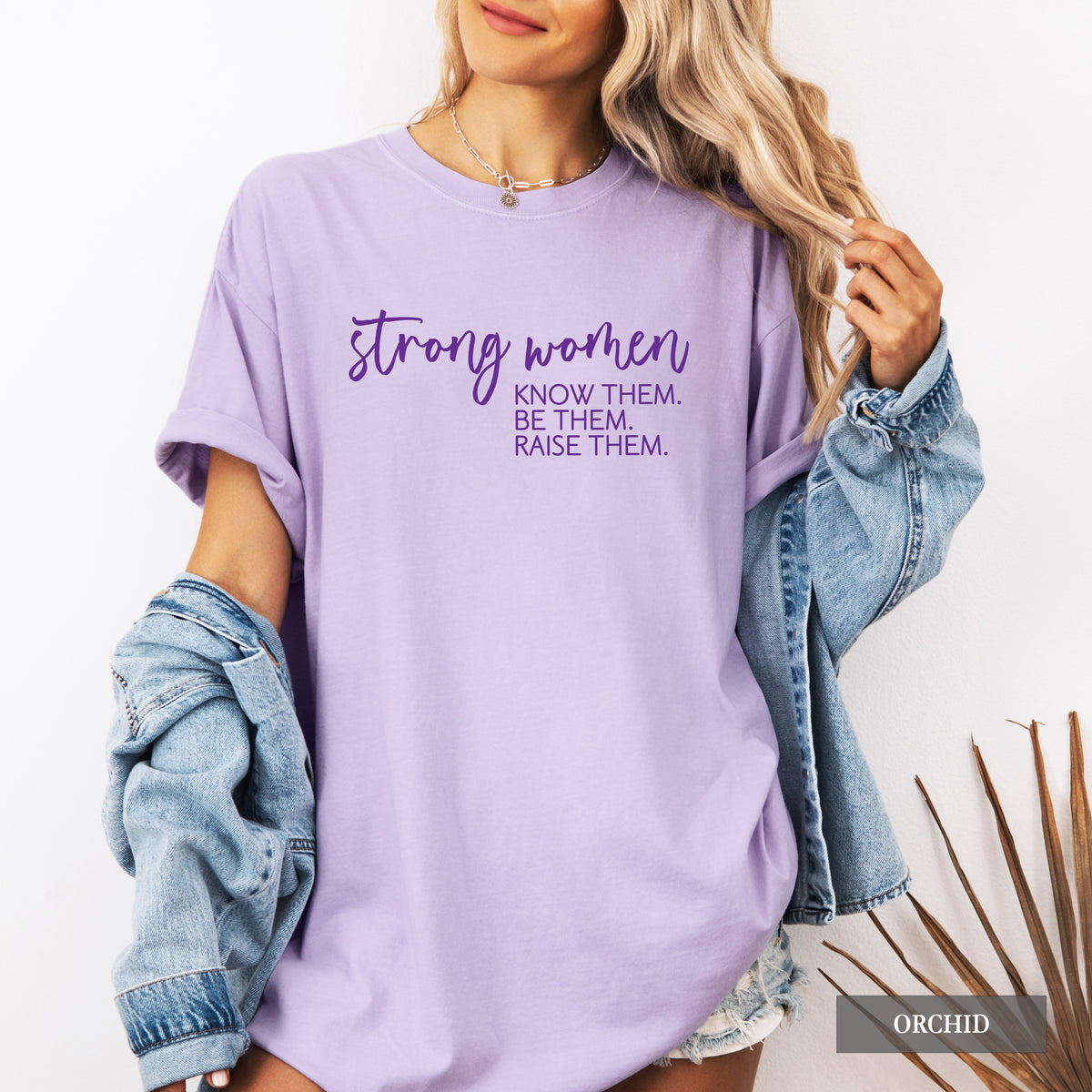 A woman wearing an orchid comfort colors shirt that says 'Strong Women Know Them Be Them Raise Them.
