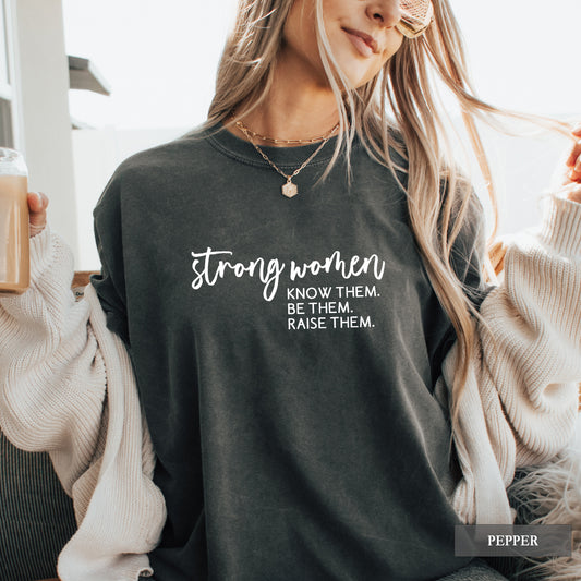 A woman wearing a pepper comfort colors shirt that says 'Strong Women Know Them Be Them Raise Them.
