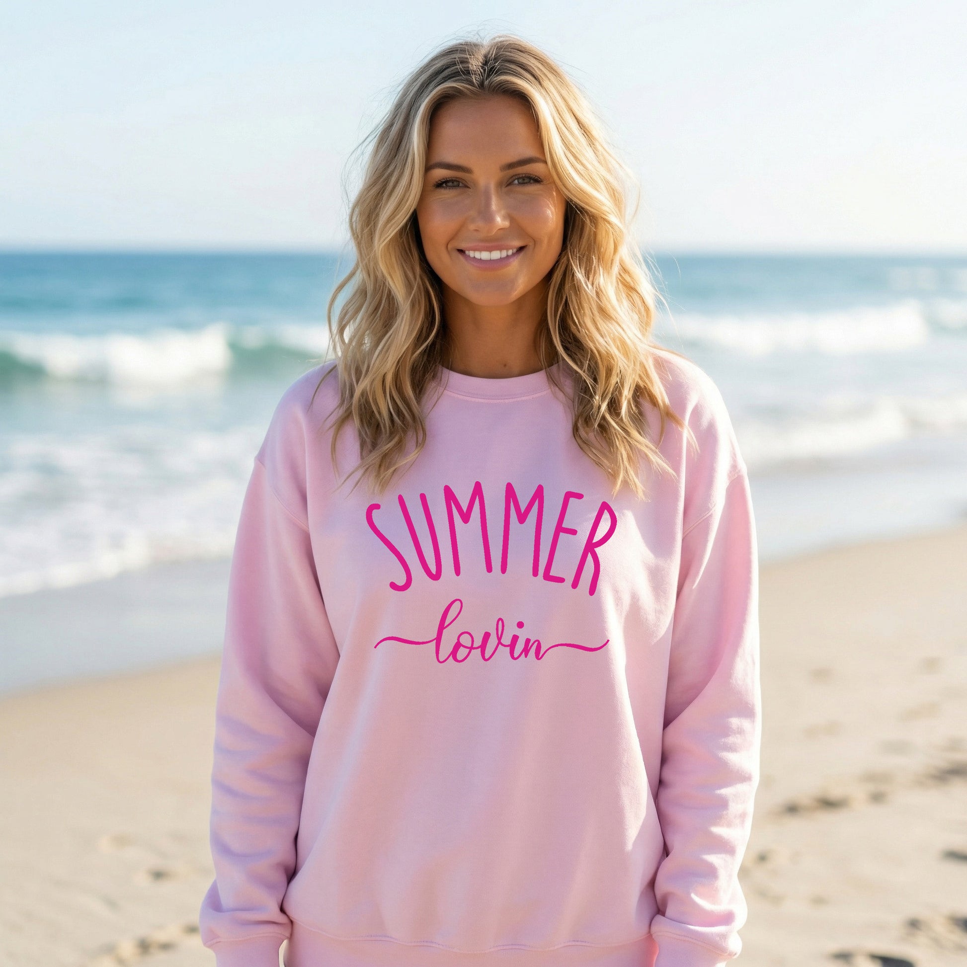 Woman wearing a light pink Gildan sweatshirt that says Summer Lovin on it.
