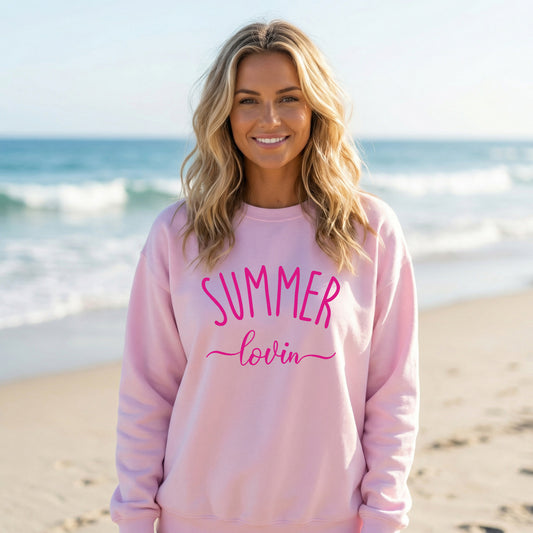 Woman wearing a light pink Gildan sweatshirt that says Summer Lovin on it.